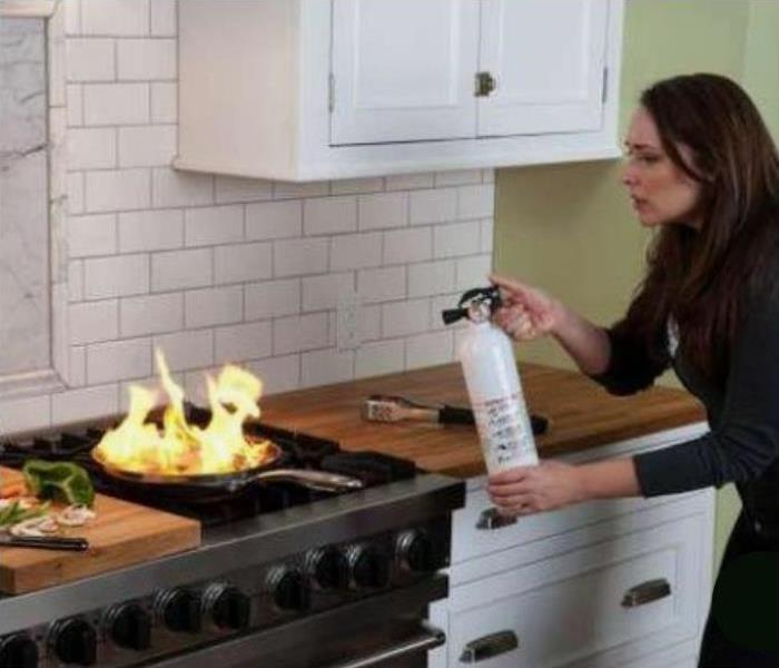 Woman with Fire Extinguisher in Kitchen